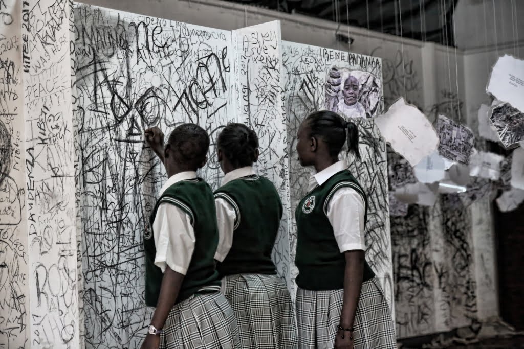 Kenyan girls in school uniforms writing their thoughts on the walls